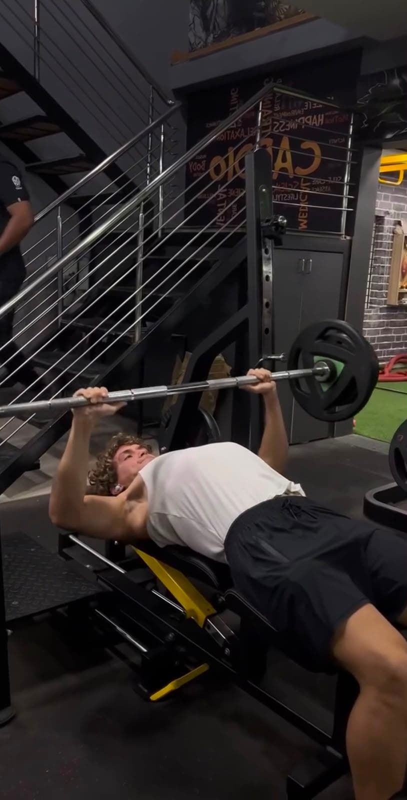 Member bench pressing near the cardio and stretch area