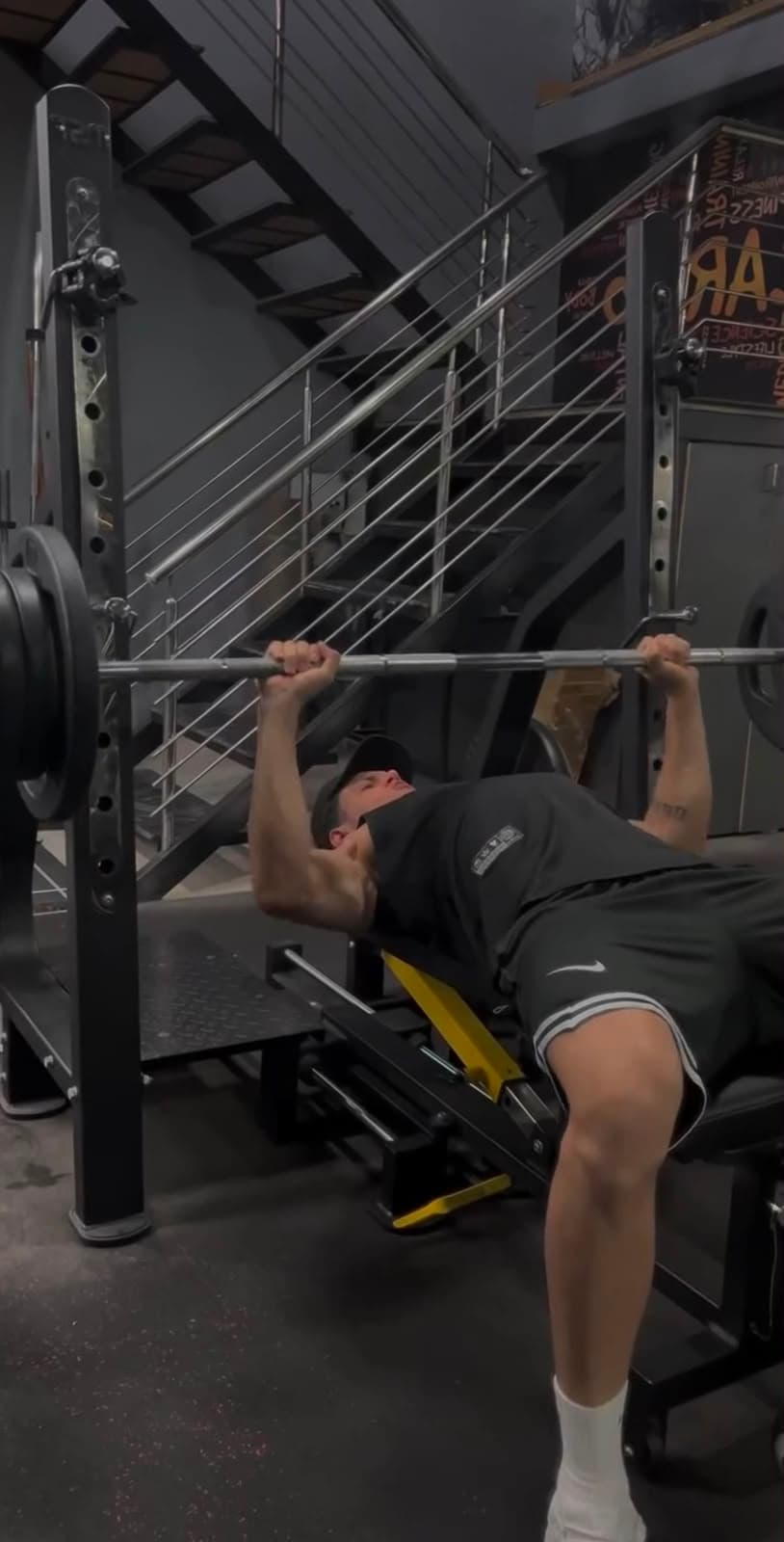Member performing a barbell back squat in the rack